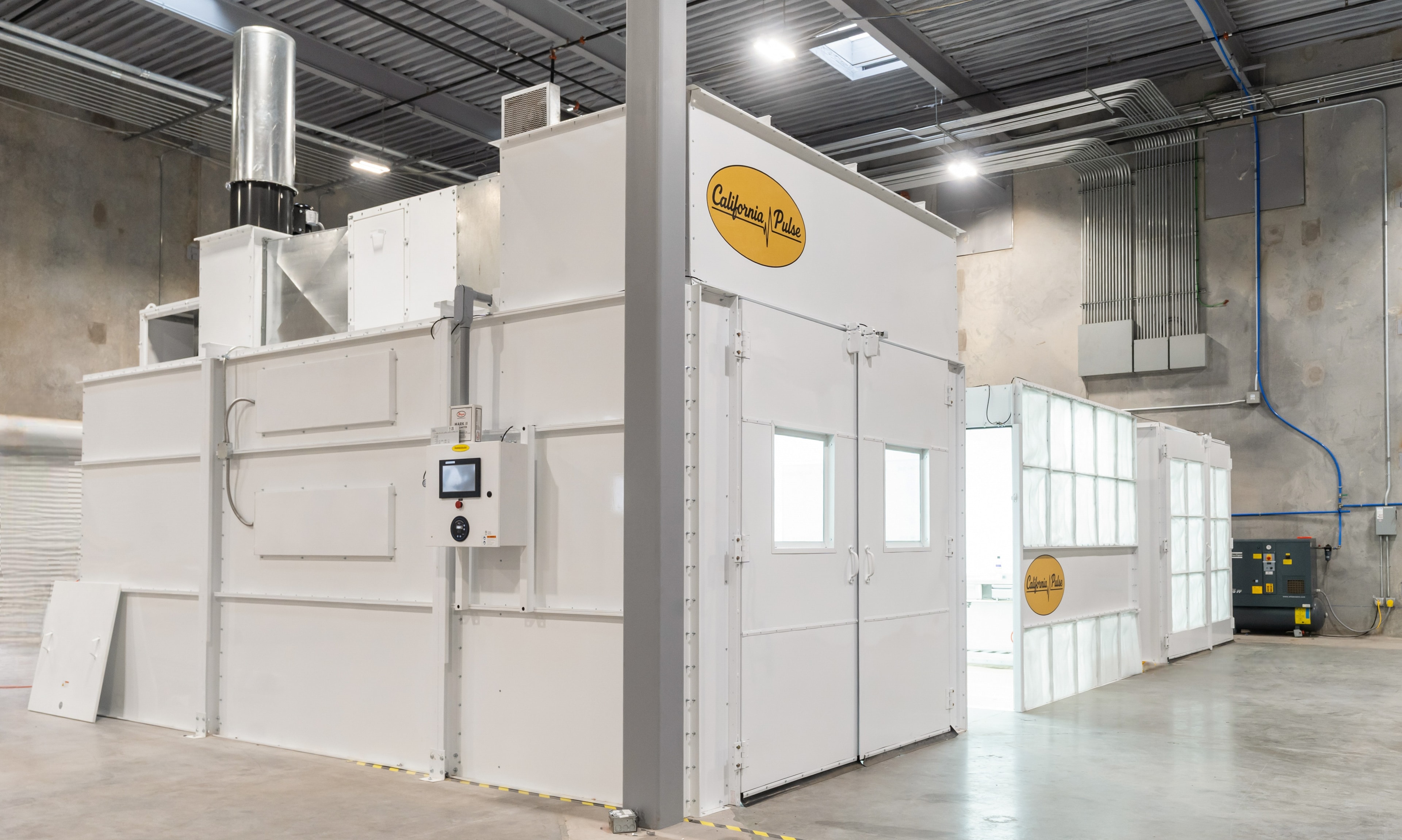 Complete California Pulse finishing system installed in a manufacturing facility with control panel and filtered air handling