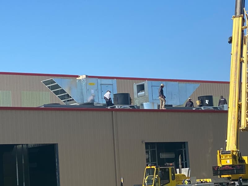A crane setting air makeup units onto the roof of a finishing facility